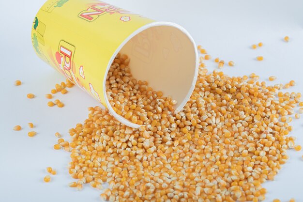 A bucket with raw popcorn on black.