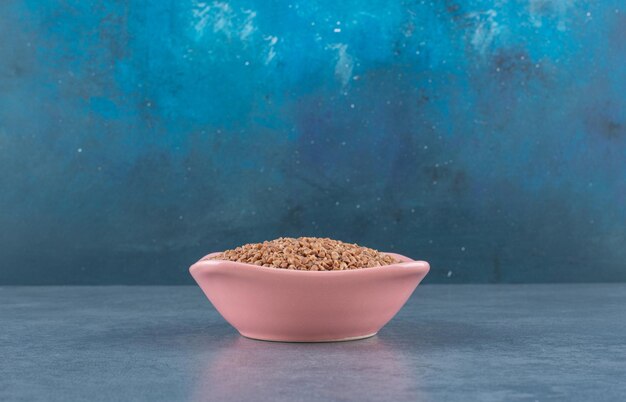 Buckwheat heaped in a pink bowl on blue