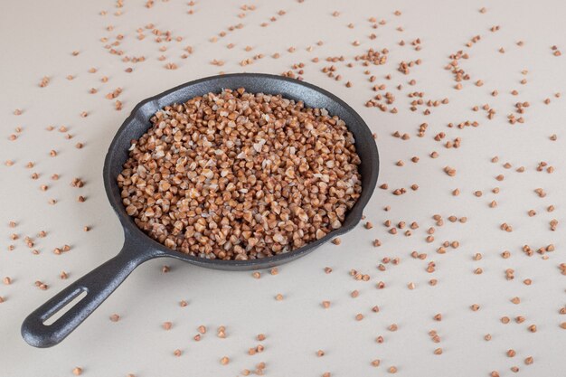 Buckwheat seeds in a black metallic pan.