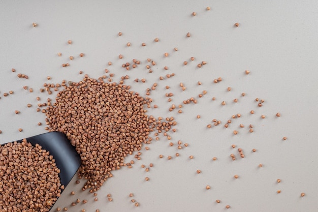 Buckwheat seeds in a cup on concrete.