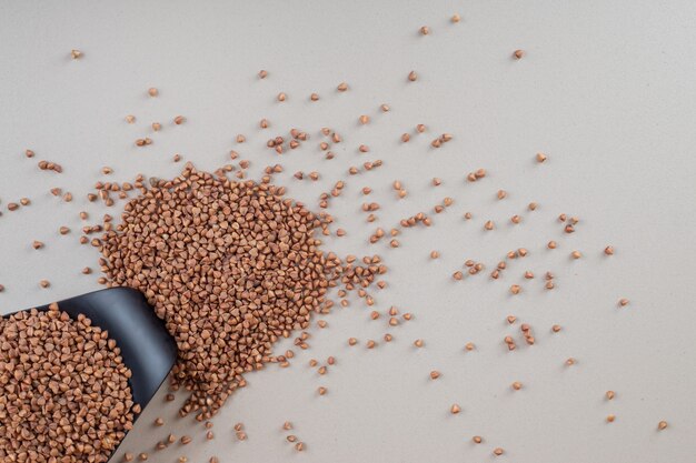 Buckwheat seeds in a cup on concrete.