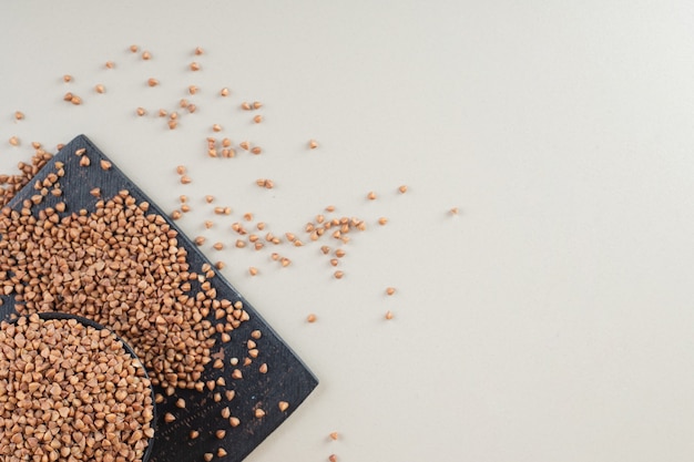 Buckwheat seeds in a dish on concrete.