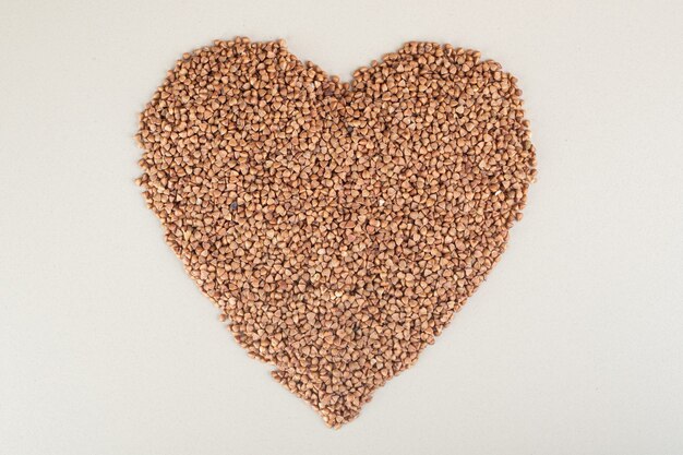 Buckwheat seeds in heart shape on concrete.