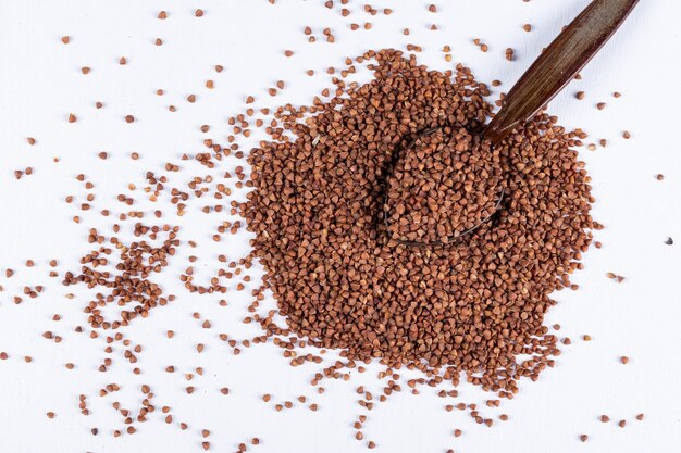 Buckwheat with spoon on them high angle view on a white 