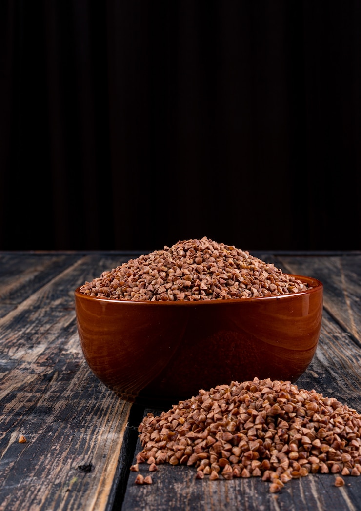 Free Photo buckwheats in a bowl and alongside, on a dark wooden . side view, vertical