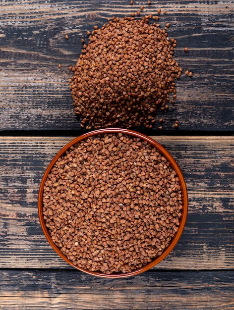 Free photo buckwheats in a bowl and next to it on a dark wooden . flat lay.