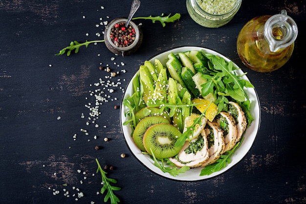 Buddha bowl dish with chicken fillet, avocado, cucumber, fresh arugula salad and sesame