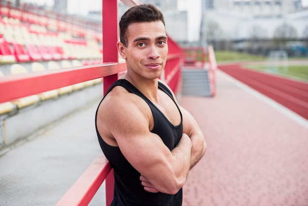 Foto gratuita costruisci l'atleta con il braccio incrociato all'atletica leggera dello stadio