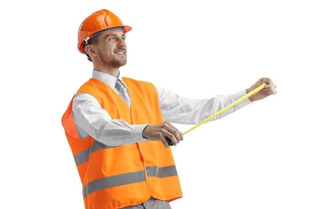 The builder in a construction vest and orange helmet standing on white studio