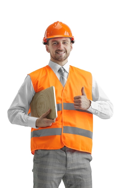 The builder in a construction vest and an orange helmet with laptop. Safety specialist, engineer, industry, architecture, manager, occupation, businessman, job concept