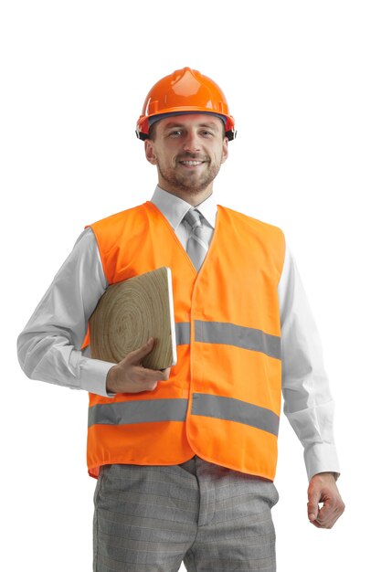 The builder in a construction vest and an orange helmet with laptop.