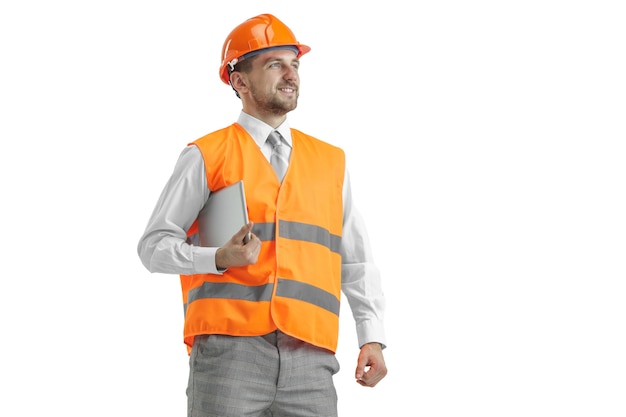 The builder in a construction vest and an orange helmet with tablet. Safety specialist, engineer, industry, architecture, manager, occupation, businessman, job concept