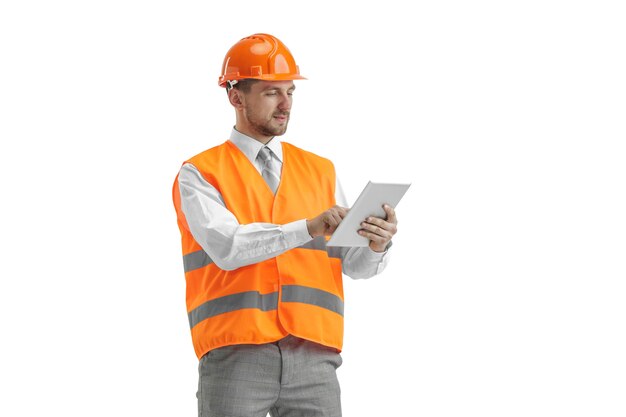 Строитель в строительном жилете и оранжевом шлеме с планшетом.