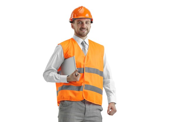 The builder in a construction vest and an orange helmet with tablet.