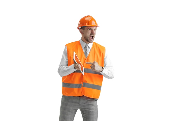 The builder in a construction vest and an orange helmet with tablet.