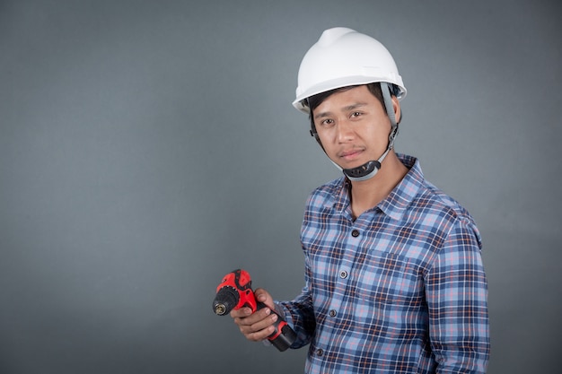 Builder holding drill on grey background