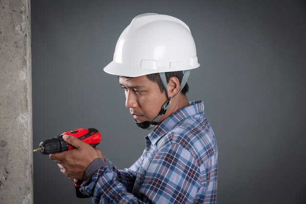 Builder holding drill on grey background