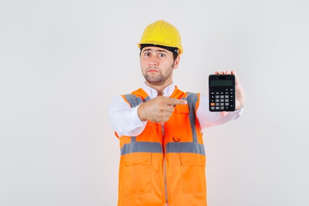 Dito puntato dell'uomo del costruttore alla calcolatrice in camicia, uniforme e che sembra ansioso, vista frontale.