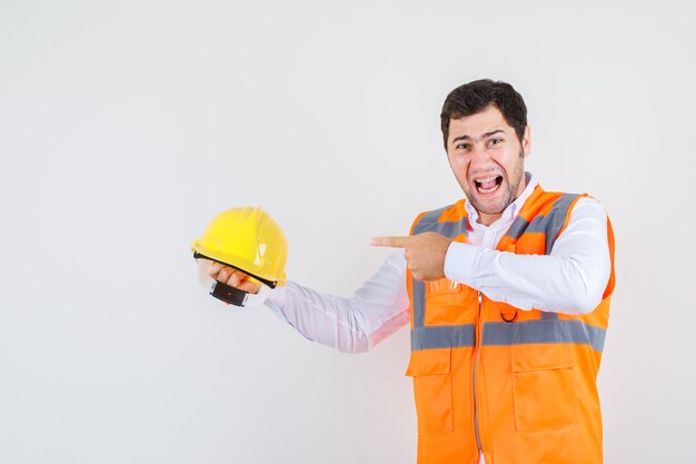 Builder man yelling while pointing finger at helmet in shirt, uniform , front view.