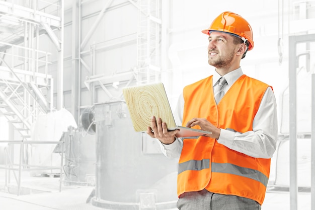The builder in orange helmet against industrial