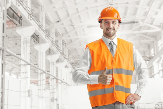 The builder in orange helmet against industrial