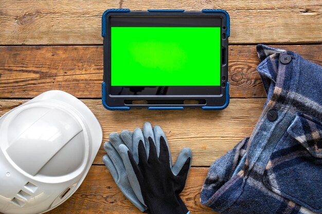 Builder uniform and digital tablet on wooden background flat lay