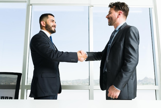 Foto gratuita costruire un lavoro di squadra collaborativo. bell'uomo d'affari e dirigente d'azienda che si conoscono mentre si stringono la mano durante una riunione di lavoro