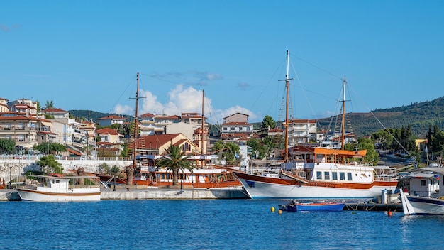 Buildings located on a hill with multiple greenery, pier with moored sailboats on the foreground, Neos Marmaras, Greece