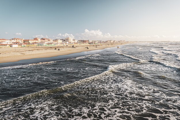 buildings on the shore near crazy sea waves