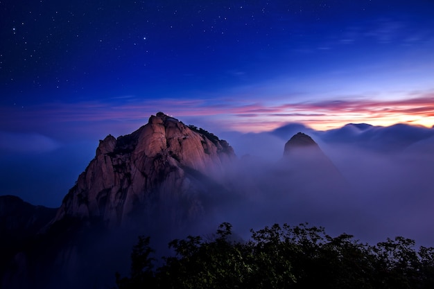 韓国のソウルにある北漢山国立公園では、北漢山の山々が朝霧と日の出に覆われています。