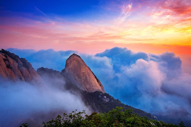 韓国のソウルにある北漢山国立公園では、北漢山の山々が朝霧と日の出に覆われています。
