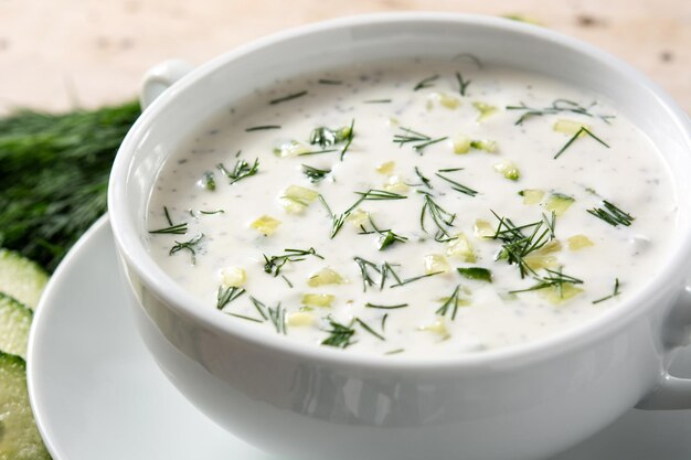 Bulgarian tarator sour milk soup in bowl on wooden table.