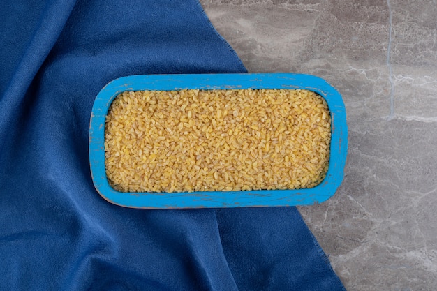 Free photo bulgur in the tray on the towel on the marble surface