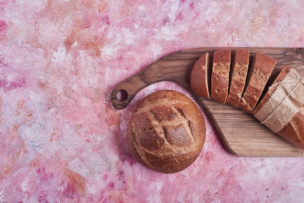 Bun and baguette on a wooden board, top view.