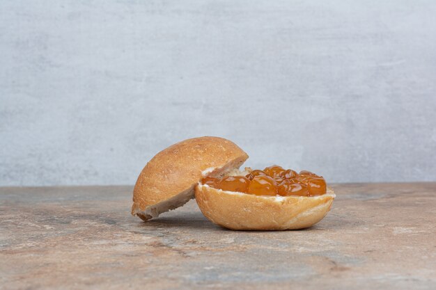 Bun and berry jam on marble table