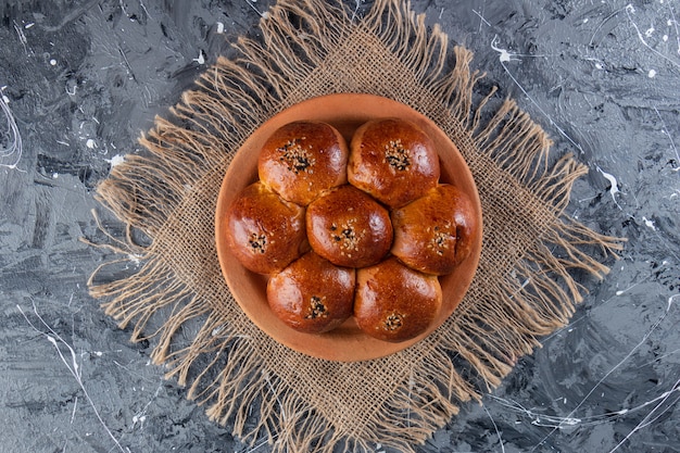 Free photo bun chamomile with poppy seeds placed on a clay plate