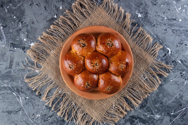 Булочка ромашка с маком на глиняной тарелке