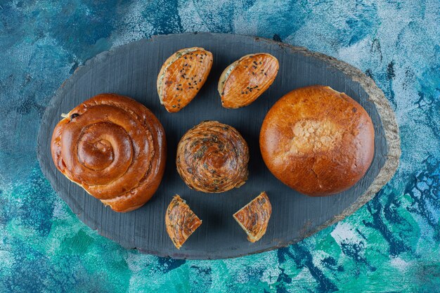 Bun, cookie and cheesy pastry on board , on the marble table. 