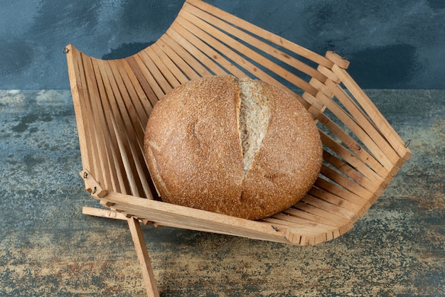 A bun of fresh brown bread on wooden basket 