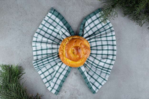 Bun and towel in a bow tie arrangement on marble surface