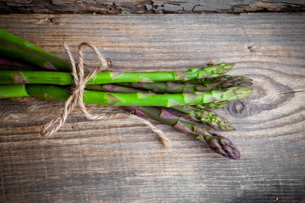 Bunch of asparagus top view on a wooden background