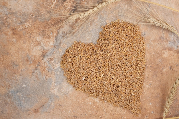 Bunch of barley formed like heart on orange space. 