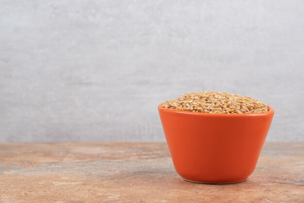 Bunch of barley in red bowl on orange background