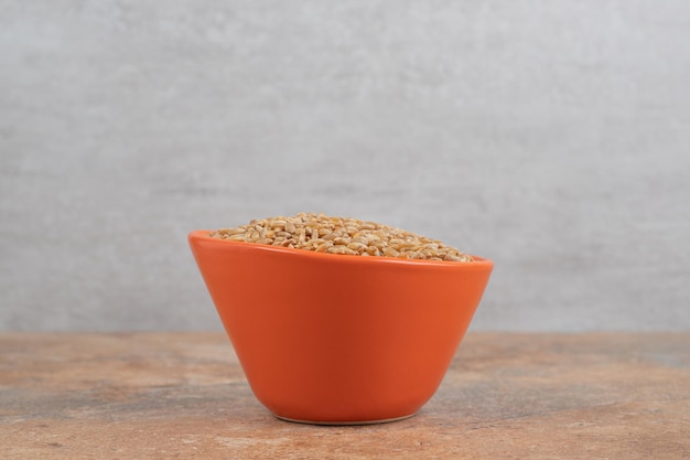 Free photo bunch of barley in red bowl on orange space.