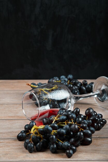 Гроздь черного винограда и бокал вина на темном фоне. Фото высокого качества