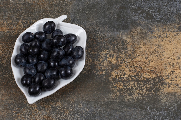 Bunch of black grapes on leaf shaped plate.