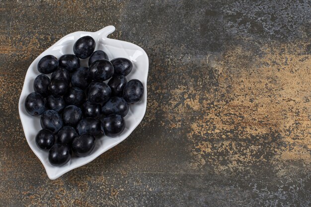 Bunch of black grapes on leaf shaped plate.