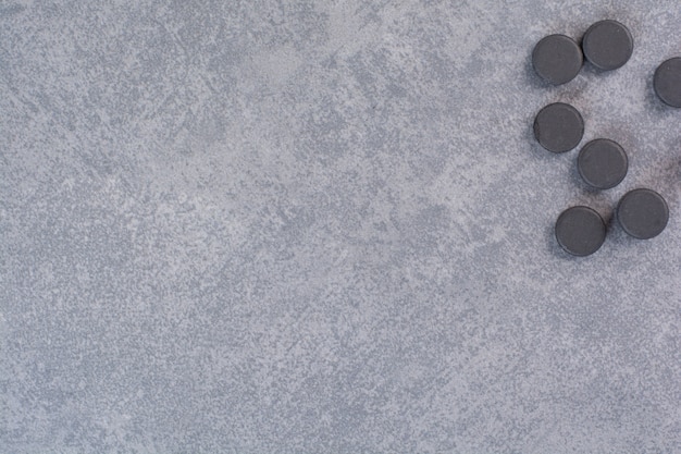 Bunch of black pills on marble table.