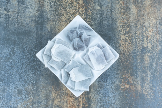 Free photo bunch of black teabags on white plate.