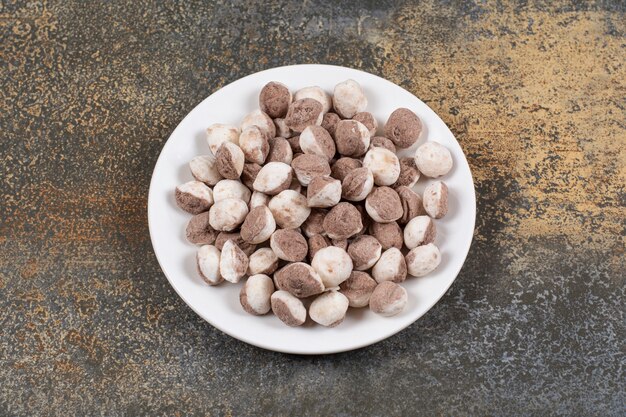 Bunch of brown candies on white plate. 